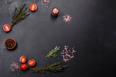 Kaburgalarda taze çiğ domuz eti, baharatlar ve ahşap kesme tahtasındaki otlar koyu beton arka planda.