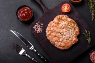 Lezzetli taze ızgara hindi eti. Baharat ve otlarla birlikte koyu beton arka planda.