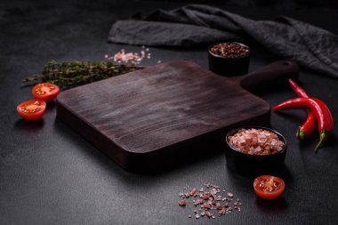 Lezzetli ızgara domuz bifteği, baharatlar ve otlar ahşap bir kesim tahtasının üzerinde.