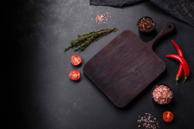 Lezzetli ızgara domuz bifteği, baharatlar ve otlar ahşap bir kesim tahtasının üzerinde.