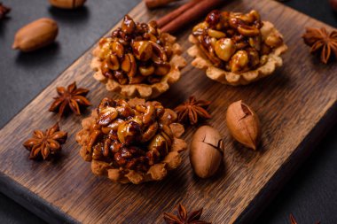 Koyu beton arka planda bal ve fındıklı tatlı bir tart. Lezzetli besleyici tatlılar