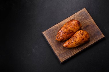 Lezzetli ızgara tavuk filetosu. Baharat ve otlarla kaplı. Koyu beton bir arka plan.