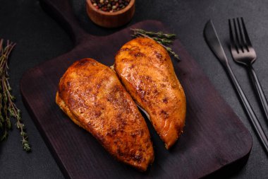 Lezzetli ızgara tavuk filetosu. Baharat ve otlarla kaplı. Koyu beton bir arka plan.