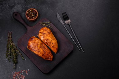 Lezzetli ızgara tavuk filetosu. Baharat ve otlarla kaplı. Koyu beton bir arka plan.