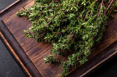 Bir grup taze kekik koyu beton arka planda toplanmış. Et pişirmek için baharat ve otlar.