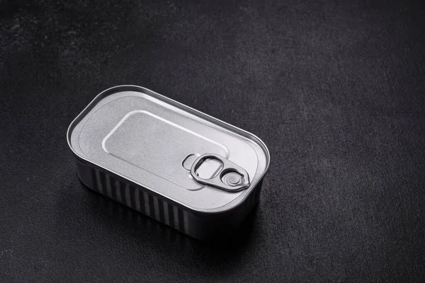 Tin or aluminum rectangular can of canned food with a key on a dark concrete background