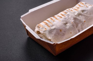 Lezzetli taze shawarma domates, biber, salatalık ve soslu koyu beton arka planda. Fast food