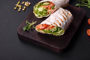 Lezzetli taze shawarma domates, biber, salatalık ve soslu koyu beton arka planda. Fast food