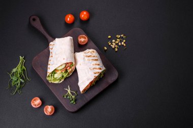 Lezzetli taze shawarma domates, biber, salatalık ve soslu koyu beton arka planda. Fast food