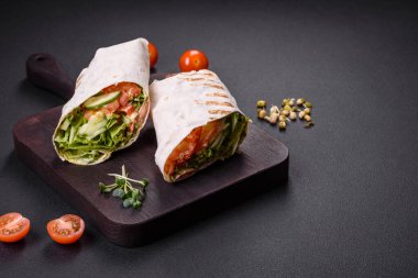 Lezzetli taze shawarma domates, biber, salatalık ve soslu koyu beton arka planda. Fast food