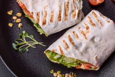 Lezzetli taze shawarma domates, biber, salatalık ve soslu koyu beton arka planda. Fast food