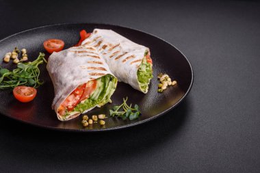 Lezzetli taze shawarma domates, biber, salatalık ve soslu koyu beton arka planda. Fast food