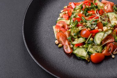 Lezzetli taze salata, domates, biber, salatalık, mikro yeşil ve siyah seramik tabakta filizlenmiş mung fasulyesi.