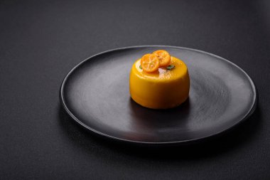 Delicious fresh tartlet with citrus filling and decorated with passion fruit on a black plate