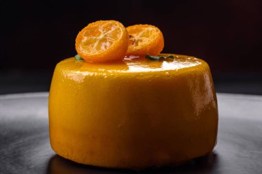 Delicious fresh tartlet with citrus filling and decorated with passion fruit on a black plate