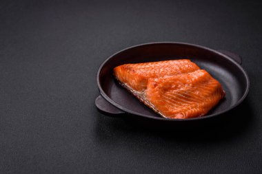 Delicious baked salmon red fish steak with spices and herbs on a dark concrete background