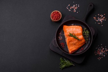 Delicious baked salmon red fish steak with spices and herbs on a dark concrete background