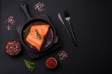 Delicious baked salmon red fish steak with spices and herbs on a dark concrete background