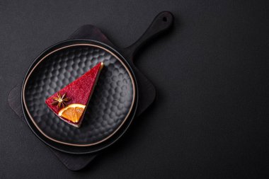 Delicious sweet cheesecake with raspberry jam on a black ceramic plate on a dark concrete background