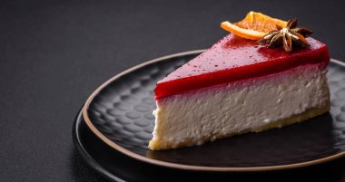Delicious sweet cheesecake with raspberry jam on a black ceramic plate on a dark concrete background