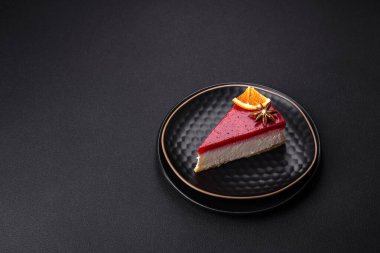 Delicious sweet cheesecake with raspberry jam on a black ceramic plate on a dark concrete background