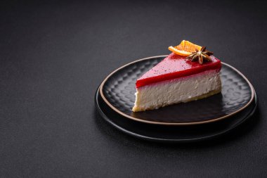 Delicious sweet cheesecake with raspberry jam on a black ceramic plate on a dark concrete background