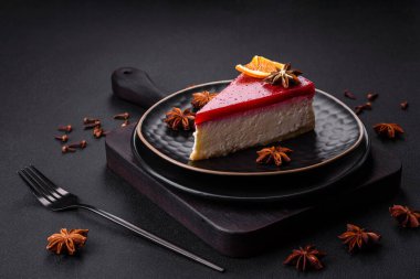 Delicious sweet cheesecake with raspberry jam on a black ceramic plate on a dark concrete background