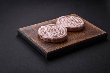 Raw meat balls with spices and herbs or crepinette on a dark concrete background