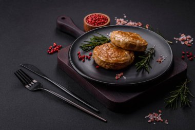 Grilled meatballs with spices and herbs or crepinette on a dark concrete background