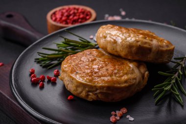 Grilled meatballs with spices and herbs or crepinette on a dark concrete background