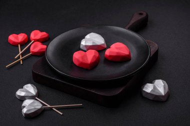 Delicious sweet heart shaped chocolate candies on a dark concrete background. Valentines day celebration
