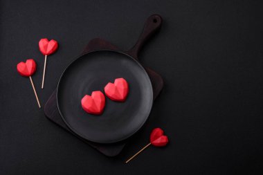Delicious sweet heart shaped chocolate candies on a dark concrete background. Valentines day celebration