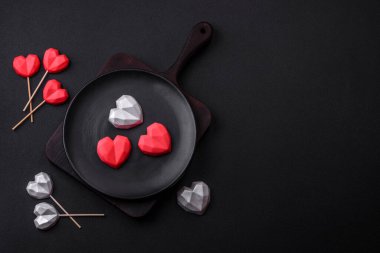 Delicious sweet heart shaped chocolate candies on a dark concrete background. Valentines day celebration