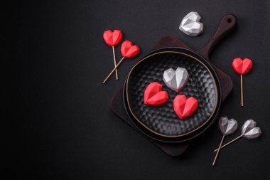 Delicious sweet heart shaped chocolate candies on a dark concrete background. Valentines day celebration