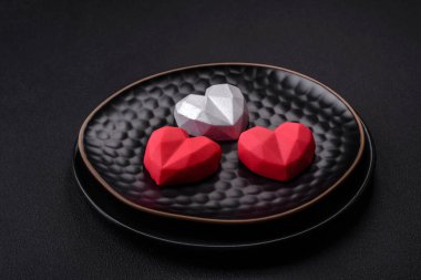 Delicious sweet heart shaped chocolate candies on a dark concrete background. Valentines day celebration
