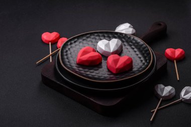 Delicious sweet heart shaped chocolate candies on a dark concrete background. Valentines day celebration
