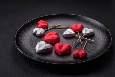Delicious sweet heart shaped chocolate candies on a dark concrete background. Valentines day celebration