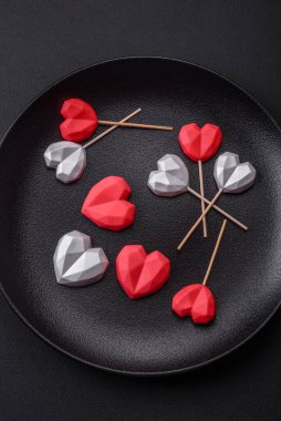 Delicious sweet heart shaped chocolate candies on a dark concrete background. Valentines day celebration