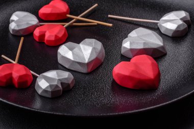 Delicious sweet heart shaped chocolate candies on a dark concrete background. Valentines day celebration