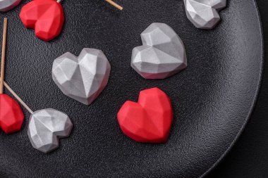 Delicious sweet heart shaped chocolate candies on a dark concrete background. Valentines day celebration