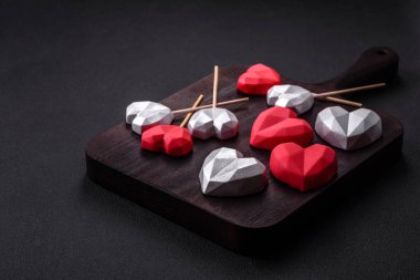 Delicious sweet heart shaped chocolate candies on a dark concrete background. Valentines day celebration