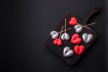 Delicious sweet heart shaped chocolate candies on a dark concrete background. Valentines day celebration