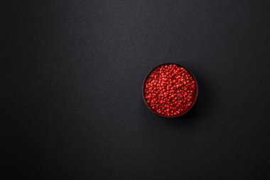 Spice, allspice peas in red or pink color in a wooden bowl on a black concrete background. Asian cuisine