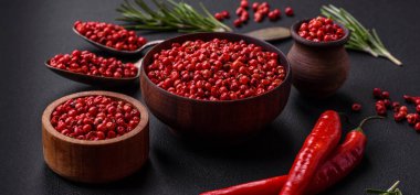 Spice, allspice peas in red or pink color in a wooden bowl on a black concrete background. Asian cuisine