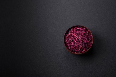 Dried beets in small slices in a wooden bowl on a black concrete background. Asian cuisine