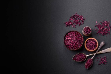 Dried beets in small slices in a wooden bowl on a black concrete background. Asian cuisine