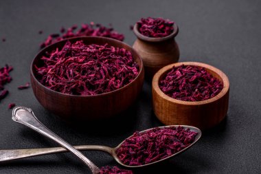 Dried beets in small slices in a wooden bowl on a black concrete background. Asian cuisine