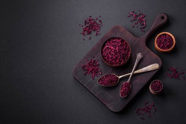 Dried beets in small slices in a wooden bowl on a black concrete background. Asian cuisine