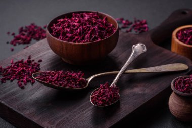 Dried beets in small slices in a wooden bowl on a black concrete background. Asian cuisine