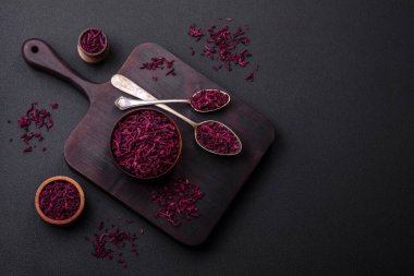 Dried beets in small slices in a wooden bowl on a black concrete background. Asian cuisine